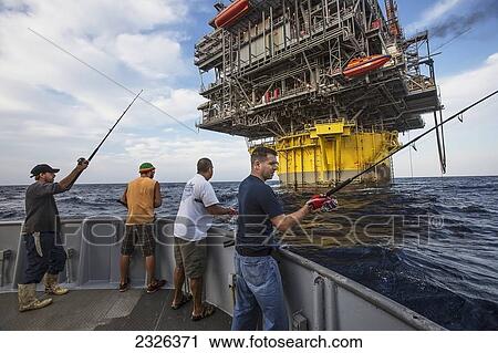 Stock Image - People fishing off boat beside perdido oil rig; Corpus christi texas usa. Fotosearch