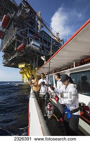 Stock Image - People fishing off boat beside perdido oil rig; Corpus christi texas usa. Fotosearch