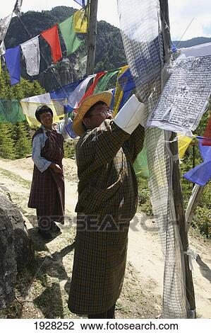 Stock Image - People Hanging Prayer Flags In Bhutan, Taktshang Goemba Tigers Nest Monastery, Bhutan. Fotosearch