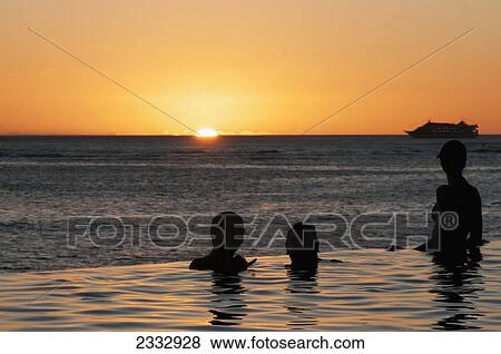 People In An Infinity Pool At The Water's Edge At Sunset Over Waikiki Beach; Honolulu, Oahu, Hawaii, United States Of America View Large Photo Image Stock Photo - People In An Infinity Pool At The Water's Edge At Sunset Over Waikiki Beach; Honolulu, Oahu, Hawaii, United States Of America. Fotosearch
