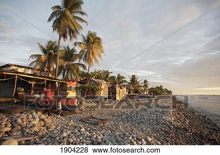 Stock Photo - People In Front Of Shacks On Beach At Sunset, Roseau, Dominica. Fotosearch