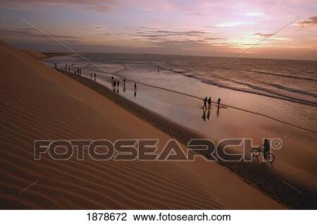 Stock Image - People In Silhouette Walking By Dunes, High Angle View. Fotosearch