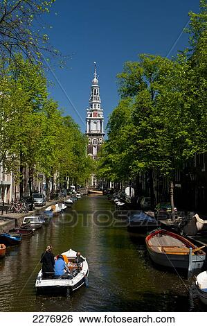 People in small boat going along small canal with spire of the Zuiderkerk church behind; Amsterdam, Holland View Large Photo Image Stock Photograph - People in small boat going along small canal with spire of the Zuiderkerk church behind; Amsterdam, Holland. Fotosearch