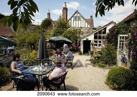 Stock Image - People In The Garden Of The King Johns Hunting Lodge And Tea Room In Lacock, Wiltshire, Uk. Fotosearch