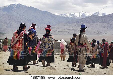 Stock Photo - People In Traditional Dress And Hats Walking Below Mountains. Fotosearch