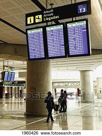 Stock Photograph - People Looking At Arrival Information Boards In The Airport; Malaga, Malaga Province, Spain. Fotosearch