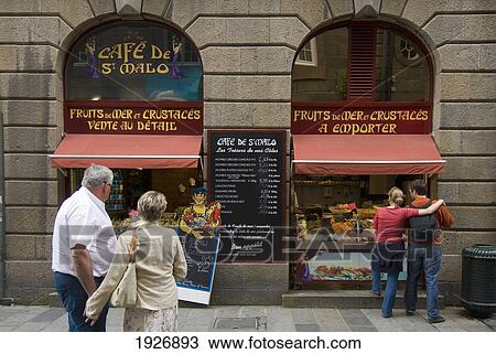 Stock Image - People Looking Into A Fish Shop In St Malo, Brittany, France. Fotosearch