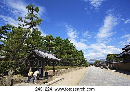 Picture - People looking into a structure on the side of a street; Japan. Fotosearch
