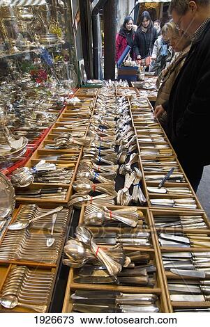 Stock Image - People Looking Through Cutlery For Sale In The Porte De Clignancourt Antiques Market, Paris, France. Fotosearch
