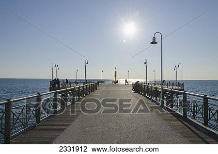 People On A Promenade Leading Out To The Water On A Sunny Day; Viareggio, Tuscany, Italy View Large Photo Image Stock Image - People On A Promenade Leading Out To The Water On A Sunny Day; Viareggio, Tuscany, Italy. Fotosearch