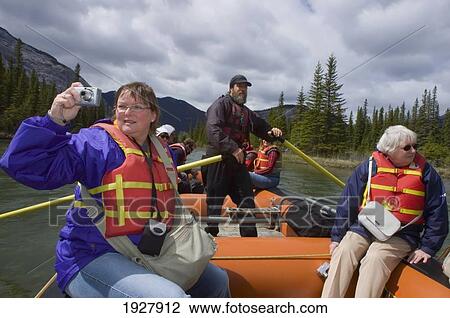 Stock Image - People On A Rocky Mountain Raft Tour Float Trip At Bow Falls, Banff National Park, Alberta, Canada. Fotosearch