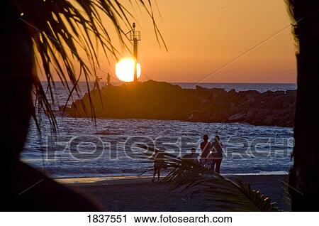 Stock Image - People On Beach At Sunset. Fotosearch