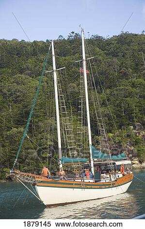 Stock Photography - People On Sail Boat Off Of Lush Island. Fotosearch