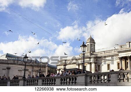 Stock Photo - People overlooking Trafalgar Square from the railing in front of The National Gallery; London, England. Fotosearch