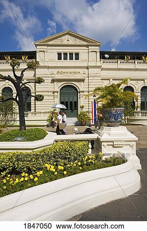 Stock Image - People Passing Royal Grand Palace In Rattanakosin District; Bangkok, Thailand. Fotosearch