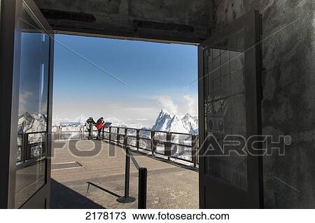 Stock Image - People Peering Over The Edge Of A Railing At The French Alps Mountain Range; Chamonix-Mont-Blanc Rhone-Alpes France. Fotosearch