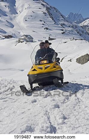 Stock Photo - People Riding A Snowmobile Around Grimsel Pass Which Offers Fantastic Views Over The Goms Valley, Southwest Switzerland. Fotosearch