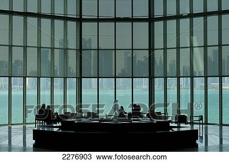 People sitting at tables in large window of the Museum of Islamic Art with view of modern skyline of Doha behind; Doha, Qatar View Large Photo Image Stock Image - People sitting at tables in large window of the Museum of Islamic Art with view of modern skyline of Doha behind; Doha, Qatar. Fotosearch