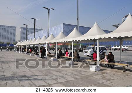 Stock Photograph - People Sitting On Benches Under White Awnings; Beijing China. Fotosearch