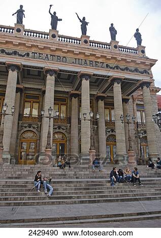 Stock Image - People sitting on the steps of an old spanish theatre with pillars and statues; Guanajuato, Mexico. Fotosearch