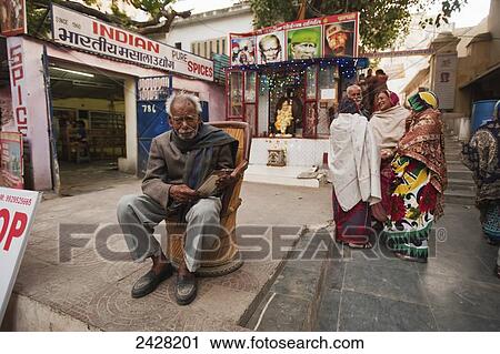 People stand talking and a man sits in a chair outside retail shops; Udaipur, India View Large Photo Image Stock Image - People stand talking and a man sits in a chair outside retail shops; Udaipur, India. Fotosearch