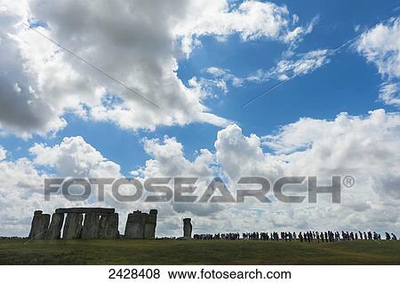 Stock Photo - People standing in a row looking around Stonehenge; Wiltshire, England. Fotosearch