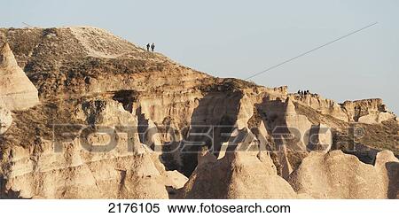 People Standing On The Ridge Of A Rugged Rock Formation; Aktepe Nevsehir Turkey View Large Photo Image Stock Photography - People Standing On The Ridge Of A Rugged Rock Formation; Aktepe Nevsehir Turkey. Fotosearch