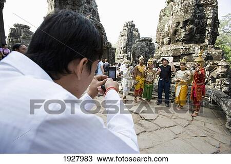 Stock Image - People Taking Picture At Iconic Bayon Temple, Siem Reap, Cambodia. Fotosearch