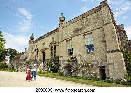 Stock Image - People Walking In Front Of The Lacock Abbey At Lacock, Wiltshire, Uk. Fotosearch