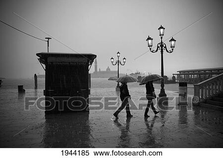 People Walking In The Rain Carrying Umbrellas With Ornate Street Lights Illuminated; Venice Venezia Italy View Large Photo Image Stock Photography - People Walking In The Rain Carrying Umbrellas With Ornate Street Lights Illuminated; Venice Venezia Italy. Fotosearch