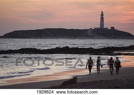 Picture - People Walking On Beach By Lighthouse At Sunset; Los CaÃƒÆ’Ã‚Â±os De Meca, Costa De La Luz, Spain. Fotosearch