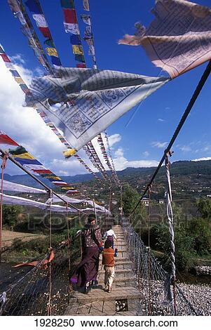 Stock Image - People Walking Through Iron Chain Brige; Paro, Paro District, Bhutan. Fotosearch