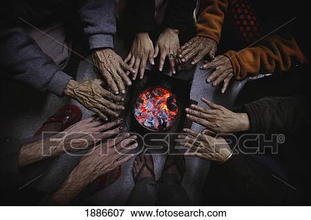 Stock Photo - People Warming Their Hands Over A Sikri, Close Up. Fotosearch