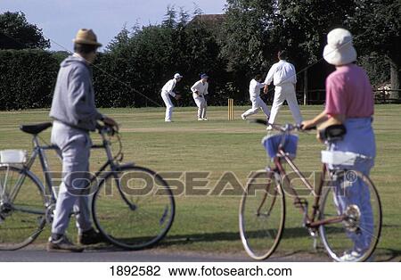 Stock Image - People With Bicycles Watching Cricket Game. Fotosearch