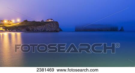 Stock Photo - Perce Rock and the town of Perce on the Gaspe Peninsula at nighttime; Perce, Quebec, Canada. Fotosearch