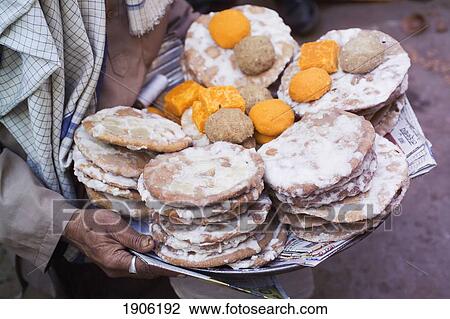 Stock Image - Person Carrying Tray With Baked Offering Food, Mid Section, Close Up, Nadhwara, Rajasthan, India. Fotosearch