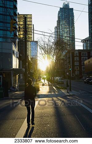 Person Crossing Street During Sunset, Downtown; Vancouver, British Columbia, Canada View Large Photo Image Stock Photo - Person Crossing Street During Sunset, Downtown; Vancouver, British Columbia, Canada. Fotosearch