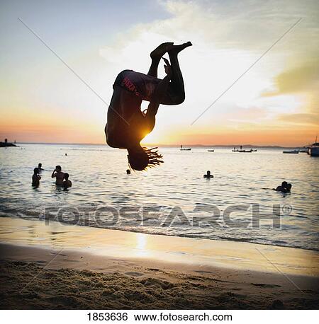 Stock Photograph - Person Doing Somersault On Beach; Salvador, Bahia, Brazil. Fotosearch