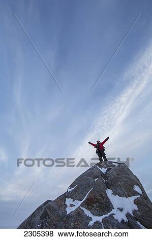 Stock Photo - Person Standing On A Large Rock With Clouds In The Sky Behind Him; Churchill Manitoba Canada. Fotosearch