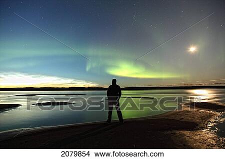 Person Standing Under The Aurora Borealis While The Mackenzie River Flows By, Fort Simpson, Nwt. View Large Photo Image Picture - Person Standing Under The Aurora Borealis While The Mackenzie River Flows By, Fort Simpson, Nwt.. Fotosearch