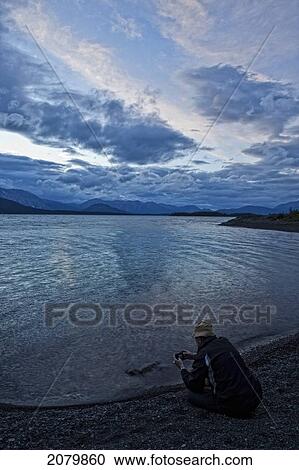 Person Taking A Picture While Sitting On The Shores Of Atlin Lake, Atlin Provincial Park, British Columbia. View Large Photo Image Stock Image - Person Taking A Picture While Sitting On The Shores Of Atlin Lake, Atlin Provincial Park, British Columbia.. Fotosearch