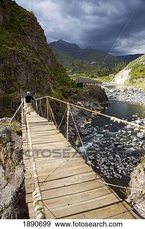 Stock Photo - Peru, Person Walking Through Suspension Bridge; Colca Valley. Fotosearch