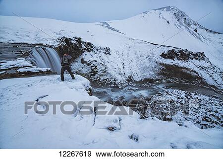 Stock Photo - Photographer taking photographs at the top of an unnamed waterfall in the highlands of Iceland; Iceland. Fotosearch