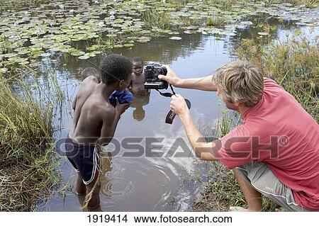 Photographer Taking Photos Of Children In River, Tanzania View Large Photo Image Picture - Photographer Taking Photos Of Children In River, Tanzania. Fotosearch