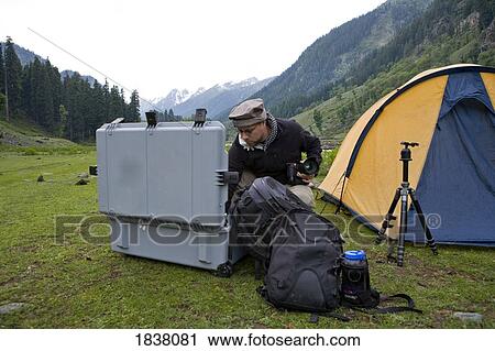 Stock Image - Photographer Unpacking Gear From Case; Lidderwat, Kashmir, India. Fotosearch