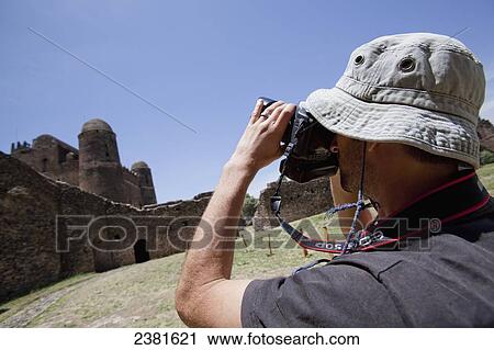 Stock Image - Photographer with camera at the seventeenth century palace of King Fasilides; Gondar, Ethiopia. Fotosearch