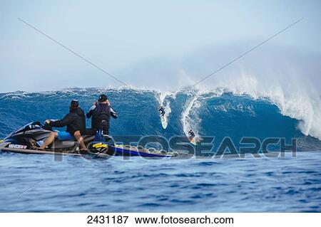 Stock Photo - Photographers watch as professional surfers surf on large waves at the infamous big wave spot know as Jaws or Peahi; Maui, Hawaii, United States of America. Fotosearch