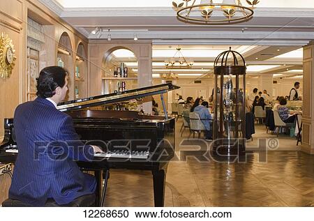 Stock Image - Pianist entertaining guests at Fortnum and Mason, Piccadilly; London, England. Fotosearch