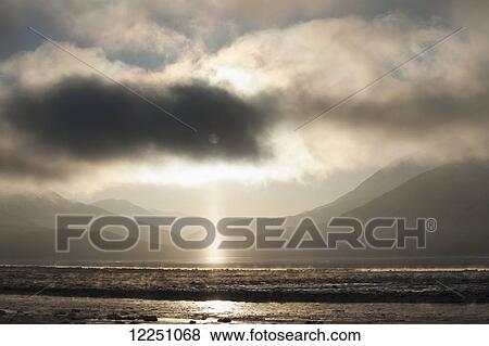 Stock Photo - Pillar of light appears as fog lifts over Turnagain Arm; Alaska, United States of America. Fotosearch