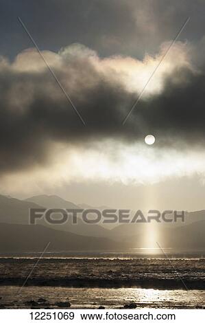 Stock Photo - Pillar of light appears as fog lifts over Turnagain Arm; Alaska, United States of America. Fotosearch